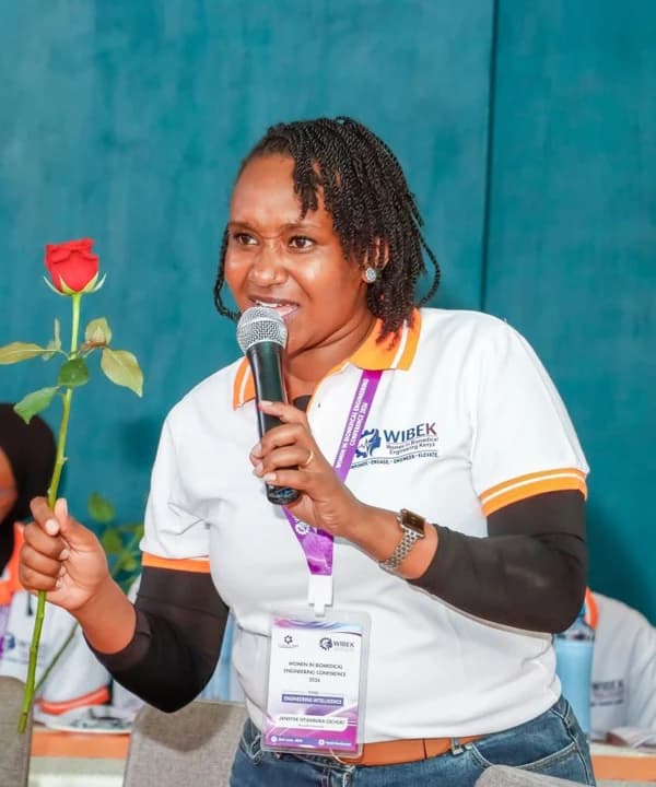 Janiffer Nyambura speaking into a microphone at the WIBEK conference