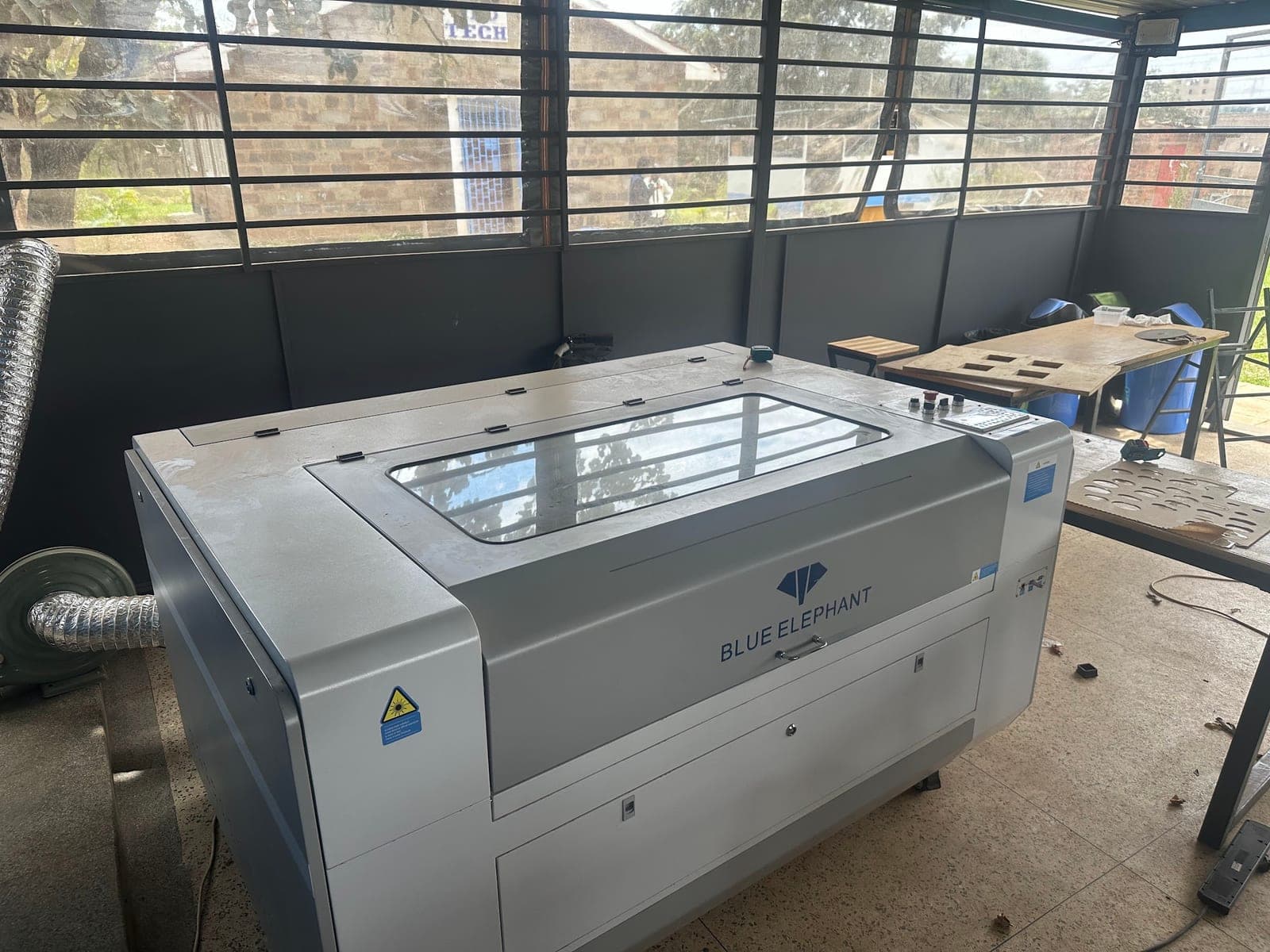 Enclosed Blue Elephant laser engraving machine beside the louvred window wall