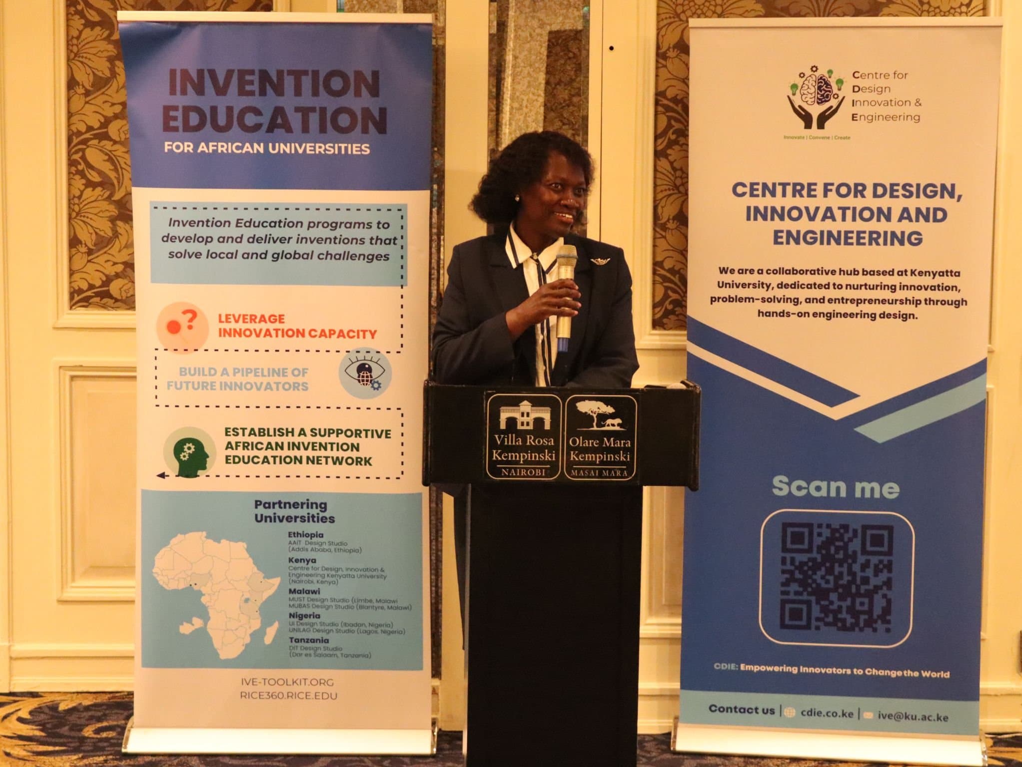 Speaker at a podium between Invention Education banners