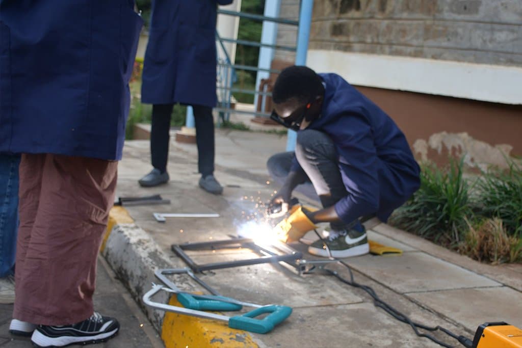 Trainee welding a frame while others watch
