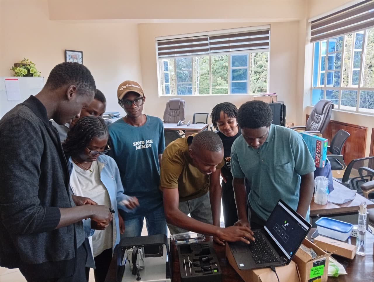 Students gathered around a laptop at a studio bench