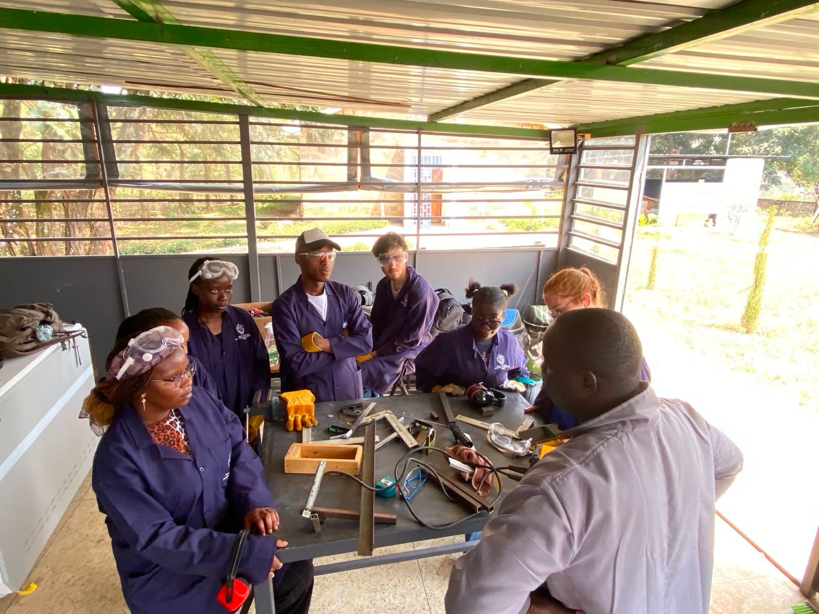 Participants in safety goggles gathered around a bench of measuring and marking tools