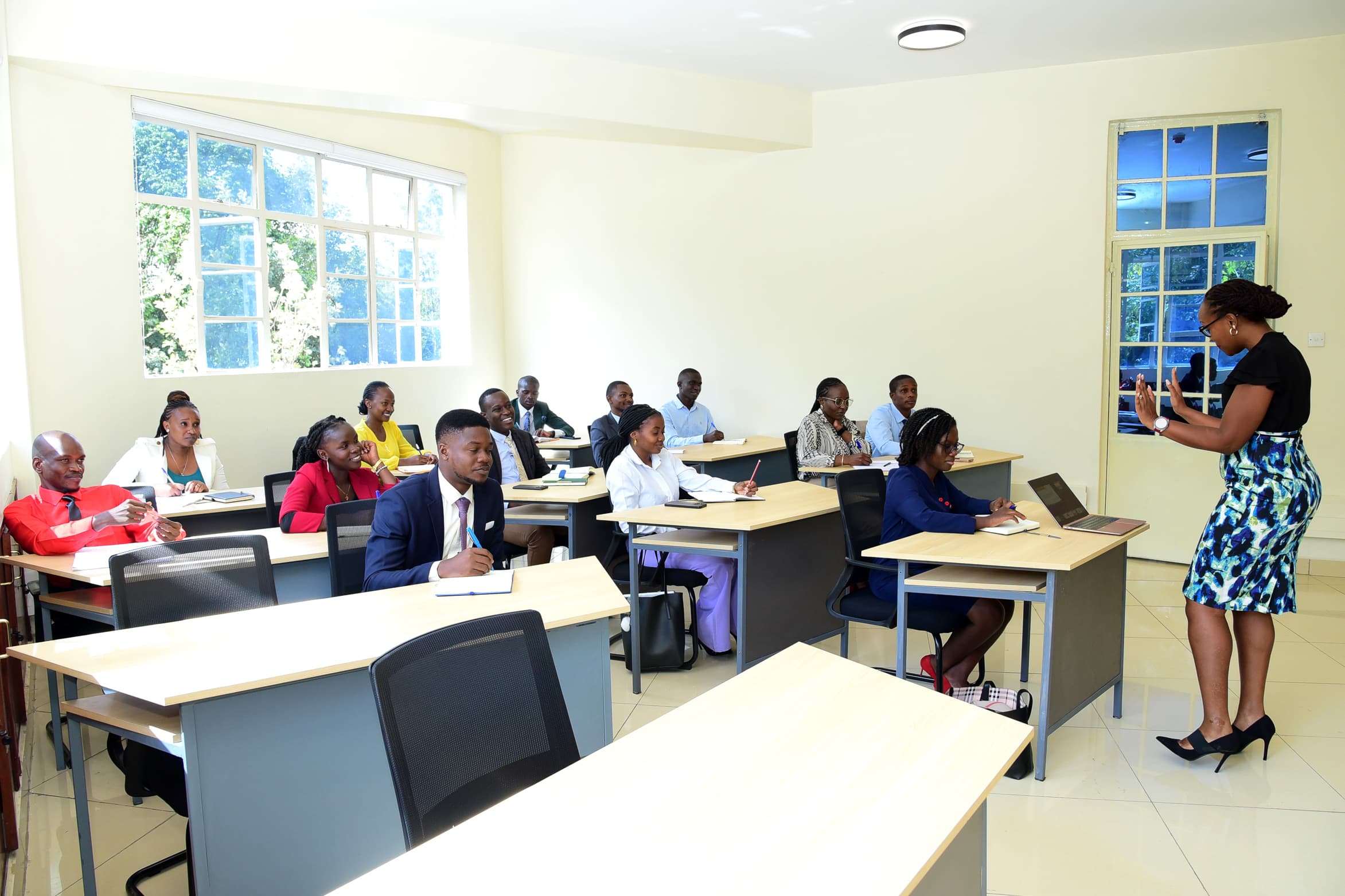 Students seated at desks in a bright seminar room while a speaker presents