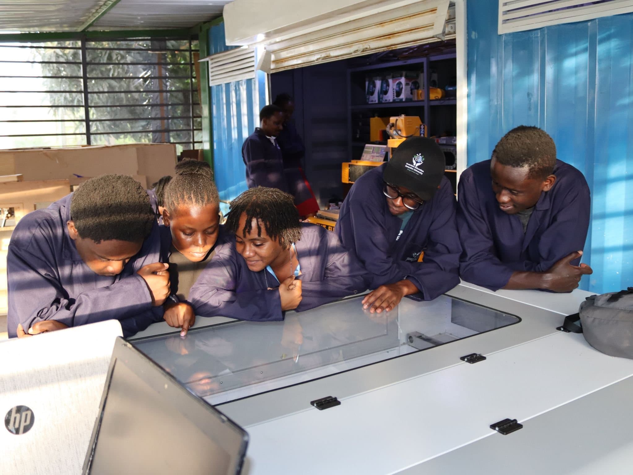 Students gathered around a laser cutter watching a job run