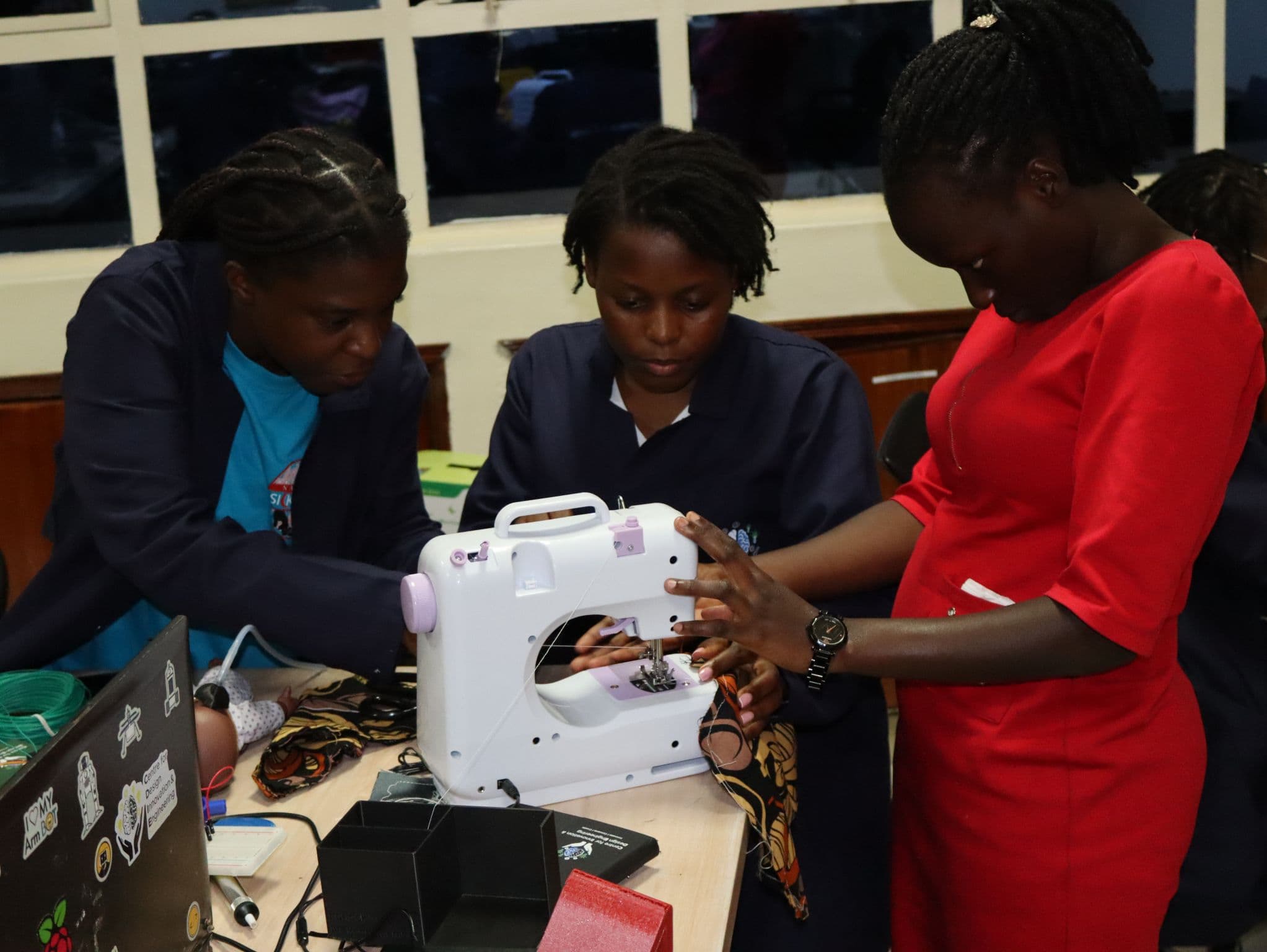 Three participants threading a sewing machine together